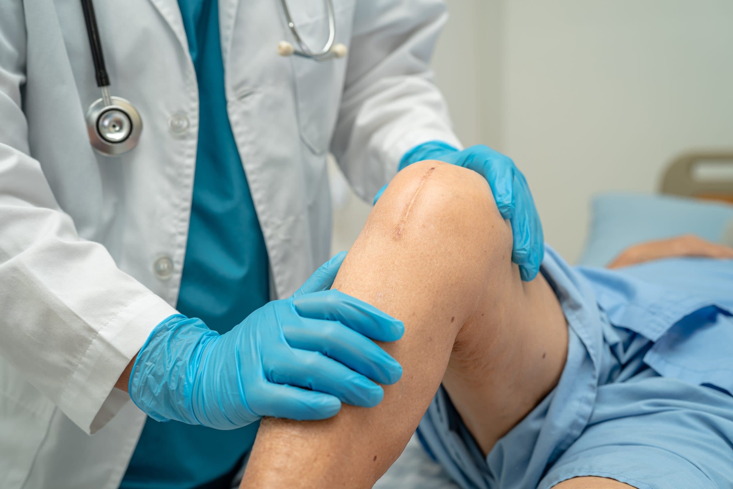 Doctor examining a patient's knee in clinic